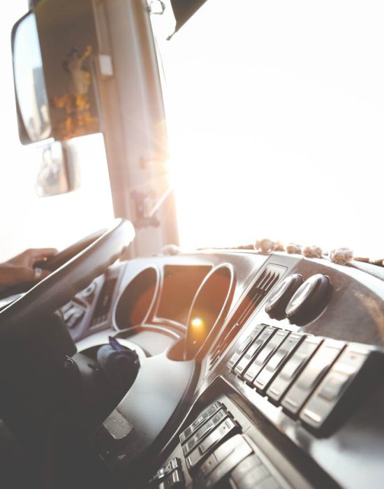 A bus driver navigating the city streets during a sunny day, focusing on the road.